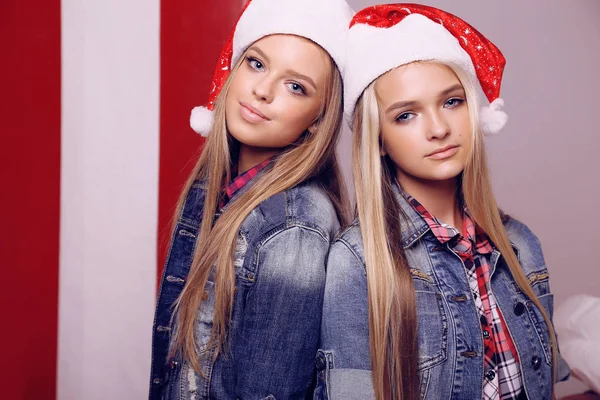 Hermosas chicas con el pelo rubio en Santa sombrero posando cerca de Christm —  Fotos de Stock