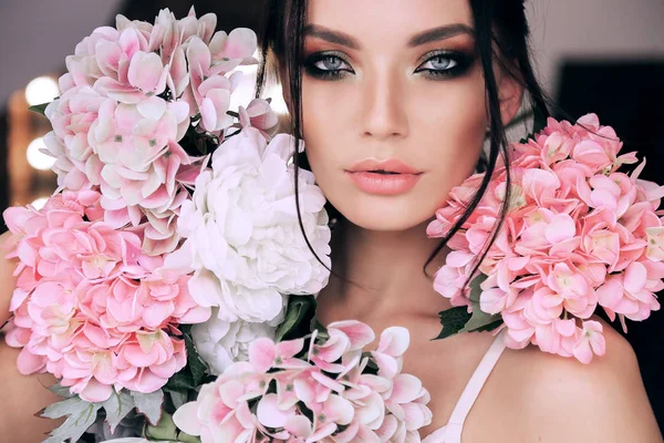 Mulher bonita com cabelo escuro e maquiagem à noite com flores — Fotografia de Stock