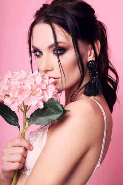 Mooie vrouw met donker haar en avond make-up met bloemen — Stockfoto