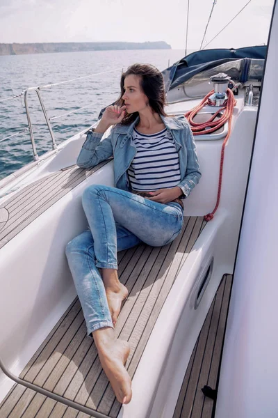 woman with dark hair in casual clothes relaxing on yacht in open