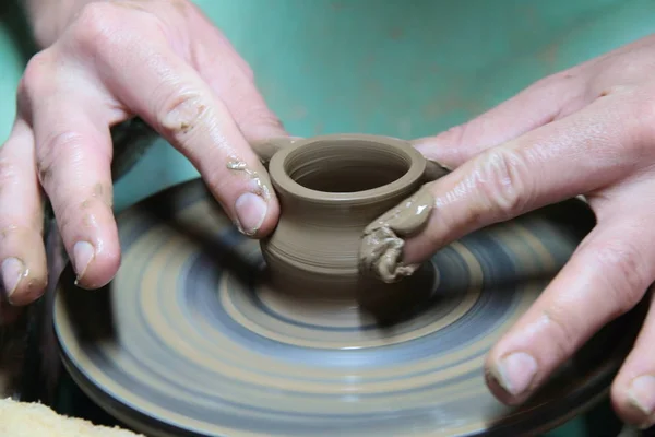 Mãos de um oleiro, criando um jarro de barro na roda de cerâmica . — Fotografia de Stock
