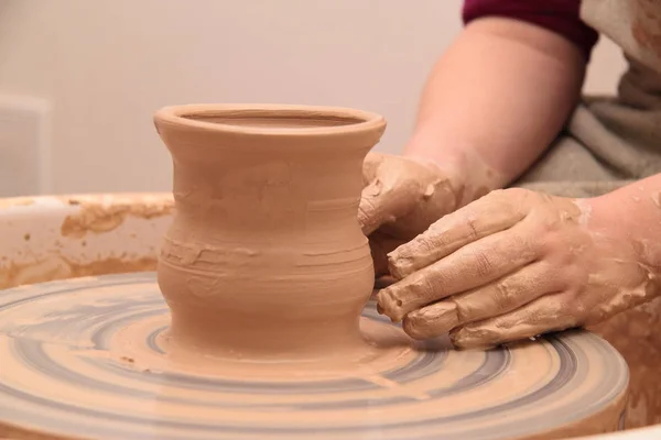 Handen van een pottenbakker, maken een aarden pot op aardewerk wiel. — Stockfoto