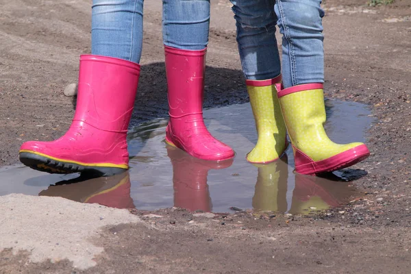 Niños piernas en jeans en botas de goma de lluvia de pie en un charco al sol — Foto de Stock