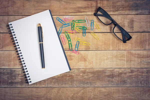 Gafas y cuaderno con bolígrafo colocado sobre una mesa de madera —  Fotos de Stock