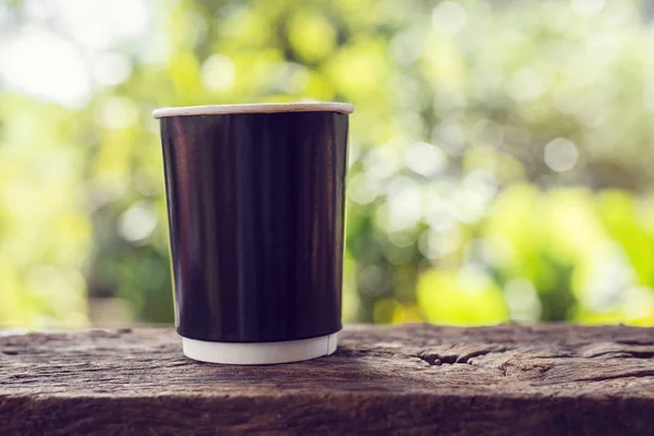 Eine Tasse Kaffee auf einem Holztisch mit Bokeh-Hintergrund — Stockfoto