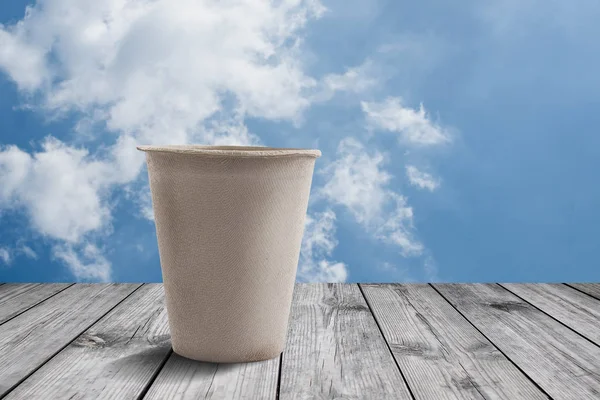 Šálek kávy na dřevěný stůl s pozadí modré oblohy — Stock fotografie