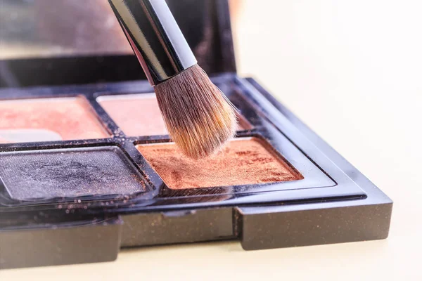 Brush for make-up over a set of eye shadow close-ups