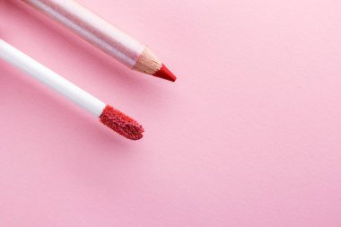 Dudak makyaj için fırça ve pembe bir arka plan üzerinde dudak makyaj için kalem. Boşaltmak