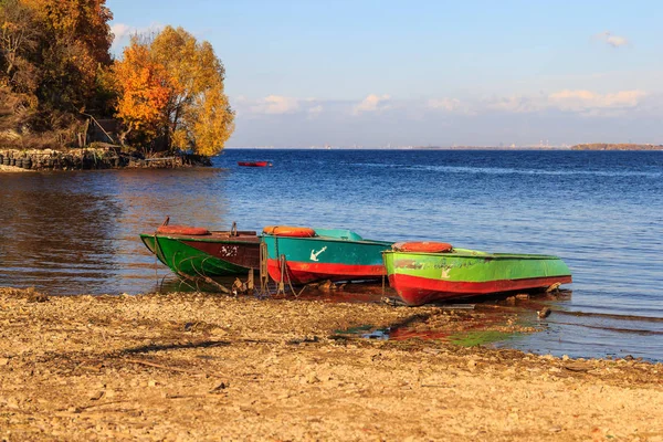 Verankert am steinigen Ufer des Bootes, verankert am Ufer vor dem Hintergrund eines bewaldeten Abhangs, eines Flusses und des Himmels. Herbst — Stockfoto