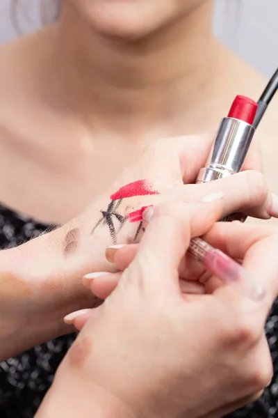 Make-up artist testuje a vybere barvu tužka na rty před použitím na povrchu modelu. Vizážista ruce rtěnku a lip liner detail vzorky — Stock fotografie
