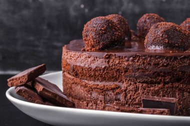 Çikolatalı bisküvi kek çikolata sır ve karanlık bir arka plan üzerinde beyaz bir tabakta kırıntıları ile dekore edilmiştir. Yakın çekim