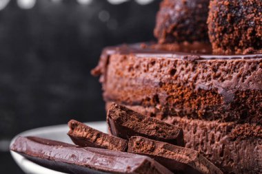 Çikolatalı bisküvi kek çikolata sır ve karanlık bir arka plan üzerinde beyaz bir tabakta kırıntıları ile dekore edilmiştir. Yakın çekim