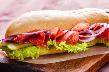 Sandviç jambon, soğan, marul ve ahşap kesme tahtası yakın çekim üzerinde turşu ile