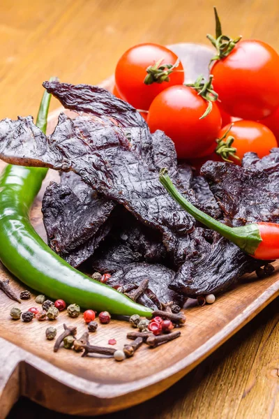 Beef jerky with vegetables and spices on a wooden tray