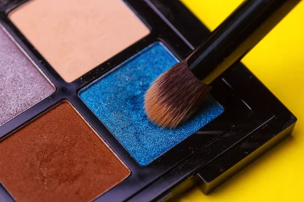 Brush for make-up over a set of eye shadow close-ups