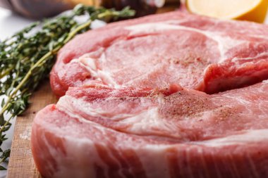 Kekik ve limon ve tuz shaker ahşap kesme tahtası üstten görünüm üzerinde bir avuç çiğ domuz doğal pirzola