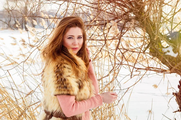 Mooie jonge vrouw in bont vest tegen de achtergrond van een winterlandschap — Stockfoto