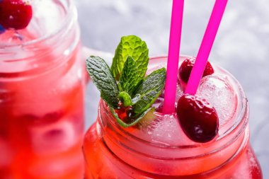 Berry Morse, frenk üzümü ve yabanmersini buz ve pudra şekeri ile kokteyl içme kavanozlara ile taze nane yaprakları ile kokteyl içme payet beton tablo yakın çekim üzerinde renkli.