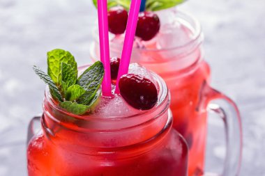 Berry Morse, frenk üzümü ve yabanmersini buz ve pudra şekeri ile kokteyl içme kavanozlara ile taze nane yaprakları ile kokteyl içme payet beton tablo yakın çekim üzerinde renkli.