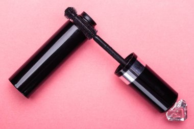 Kirpik makyaj fırça ve maskara ile boşaltmak pembe arka plan üzerinde yakın şişe