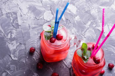 Berry Morse, frenk üzümü ve yabanmersini buz ve pudra şekeri ile kokteyl içme kavanozlara ile taze nane yaprakları ile kokteyl kamış bir beton masa üstü görünüm içme renkli