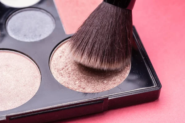Brush for make-up over a set of cosmetic powder close-up