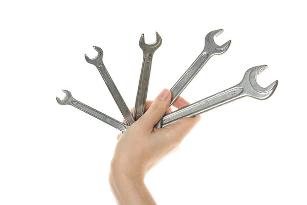 A set of vintage wrenches in a female hand is isolated on a white background