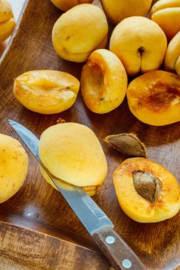 Kayısı ahşap bir tabak üzerinde bir mutfak bıçağıyla kemik üzerinden el ile temizleme işlemi. Reçel yemek pişirmek için hazırlık. Yaşam tarzı