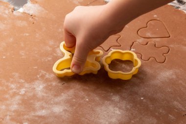 Zencefilli Noel kurabiyeleri yapmak için özel kalıplar kullanarak hamurdan figürler kesmek. Çocukların elleri, yakın plan. Ev ve aile tatil konseptine hazırlanıyor.