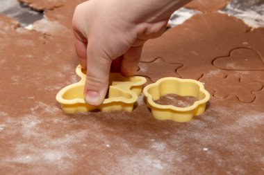 Zencefilli Noel kurabiyeleri yapmak için özel kalıplar kullanarak hamurdan figürler kesmek. Çocukların elleri, yakın plan. Ev ve aile tatil konseptine hazırlanıyor.