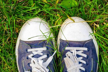 Yeşil çimlerin üzerinde eski, kirli, pejmürde spor ayakkabılar. Yürüyüş Seyahat Konsepti