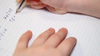 Çocuk okul ödevi yapıyor, aritmetik örnekleri çözüyor ve onları bir deftere yazıyor. Ekonomik eğitim kavramı