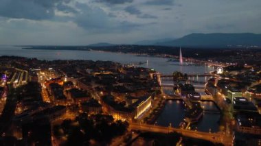 Night time 4k footage of illuminated Geneva aerial riverscape panorama with huge fountain, Switzerland  