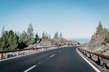 Sağdaki bulutlar yakınındaki kayalar ile o çok yeşil çam ağaçlarının karayolu geçer. Teide Milli Parkı. Tenerife