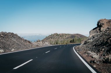 Kayalıklardan yakınındaki bulutlar arasında sağdaki kanyonda otoyol gider. Teide Milli Parkı. Tenerife
