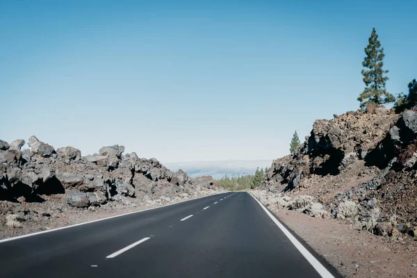 Otoyol bulutlar yakınındaki ormana büyük kayalar arasında düz gider. Teide Milli Parkı. Tenerife