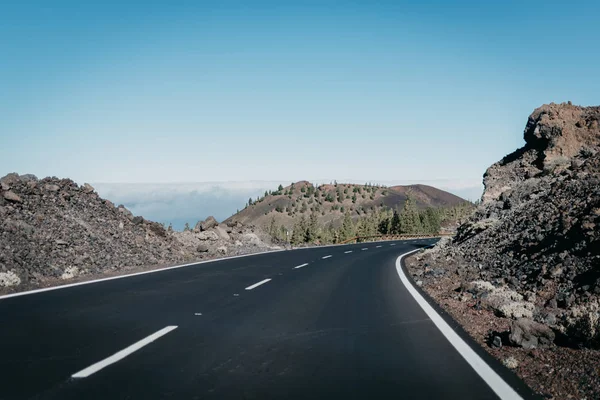 Kayalıklardan yakınındaki bulutlar arasında sağdaki kanyonda otoyol gider. Teide Milli Parkı. Tenerife