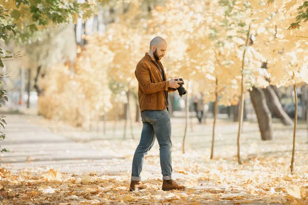 대머리의 작가가 스웨이드 파란색 청바지 부츠에 수염을 두르고 공원의 카메라에 — 스톡 사진