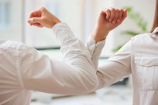 Elbow greeting to avoid the spread of coronavirus (COVID-19). Man and woman meet in an office with bare hands. Instead of greeting with a hug or handshake, they bump elbows instead.