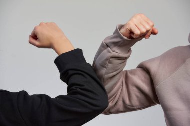 Dirsek çarpması. Coronavirus 'un (COVID-19) yayılmasını önlemek için yeni bir selamlama yöntemi. Sweatshirt giyen bir kız ve bir erkek kucaklaşmak ya da tokalaşmak yerine dirseklerini birbirine vurur.. 