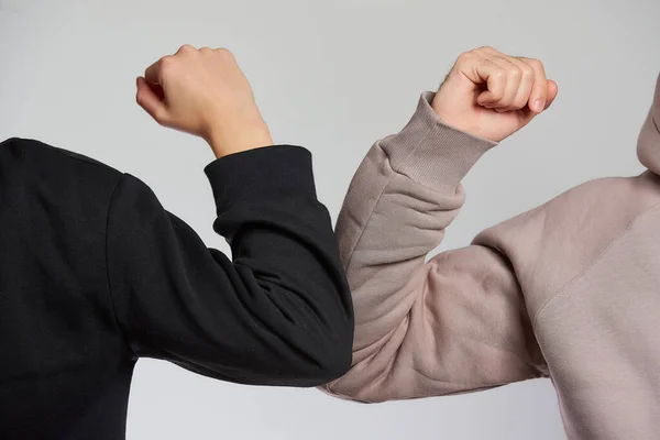 Elbow bumping. A new way of greeting to avoid the spread of coronavirus (COVID-19). A man and a woman in sweatshirts bump elbows Instead of greeting with a hug or handshake.