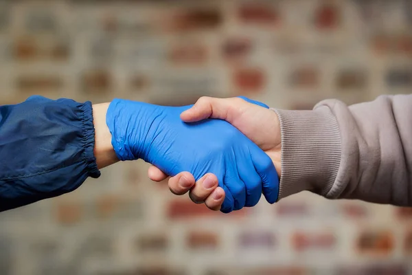 握手だ 男性と使い捨ての医療用手袋で握手女性は コロナウイルスの拡散を避けるために Covid 二人の人間が通りで会う — ストック写真