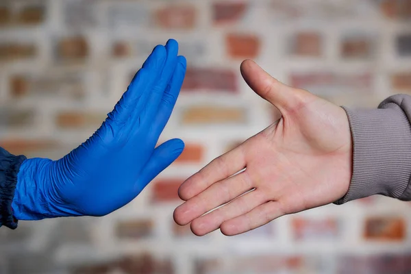 A man with naked hand offers to shake hands with a woman. A woman with hand in disposable medical glove stopping him to avoid the spread of coronavirus (COVID-19).  She doesn\'t want to shake hands.