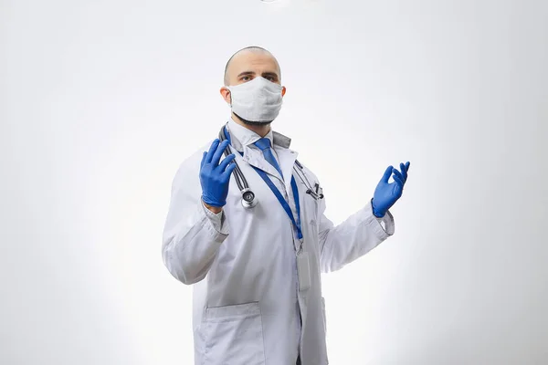 手で使い捨て医療用手袋で拡散コロナウイルス Covid を避けるために保護面マスク中の原因となる医師 あごひげを生やした医師が手術の準備をしている — ストック写真