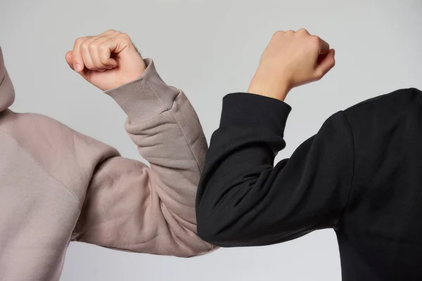 Elbow bumping. A new way of greeting to avoid the spread of coronavirus (COVID-19). A man and a woman in sweatshirts bump elbows Instead of greeting with a hug or handshake.