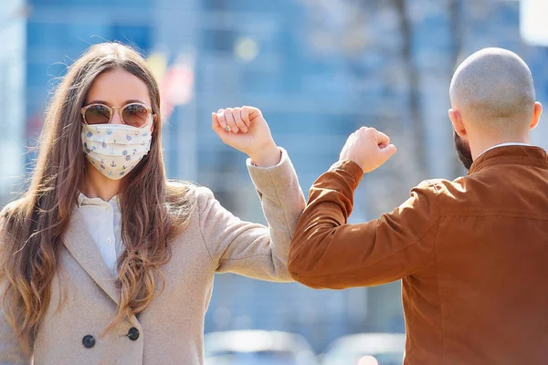 Dirsek çarpması. Coronavirus 'un (COVID-19) yayılmasını önlemek için dirsek seği selamı. Kadın ve erkek çıplak ellerle sokakta buluşurlar. Sarılmak ya da tokalaşmak yerine, dirseklerini vuruyorlar..