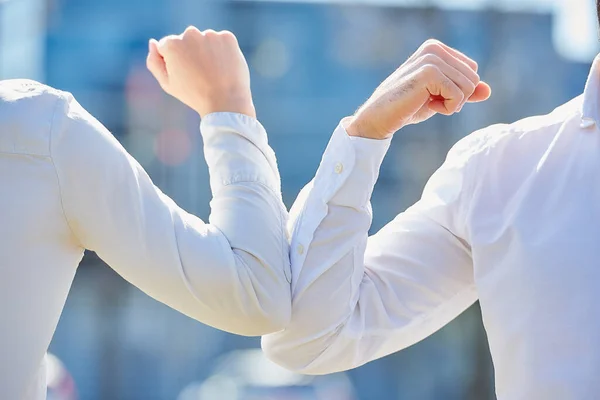 A close-up photo of elbow bumping. Elbow greeting to avoid the spread of coronavirus (COVID-19). Colleagues meet with bare hands. Instead of greeting with a hug or handshake, they bump elbows.