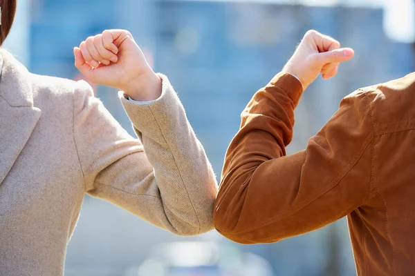 A close-up photo of elbow bumping. Elbow greeting to avoid the spread of coronavirus (COVID-19). A man and a woman meet with bare hands. Instead of greeting with a hug or handshake, they bump elbows.