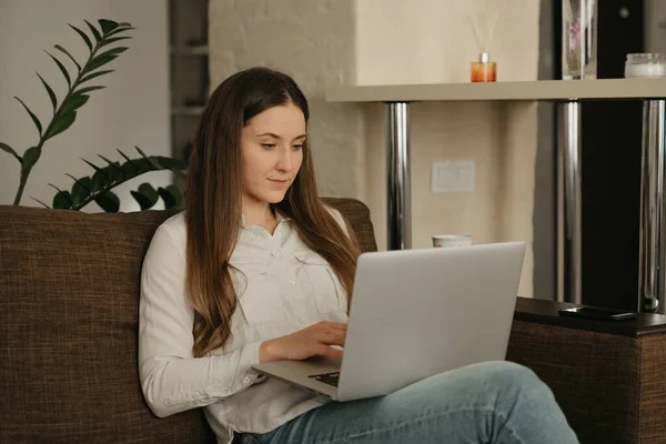 Remote work. A caucasian woman working remotely on her laptop. A businesswoman working from home on the sofa.