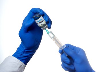 Tek kullanımlık tıbbi eldiven giymiş bir doktorun elleri bir şişeden şırıngaya koronavirüs aşısı çiziyor. Bir hastanede COVID-19 aşısı kullanmaya hazırlanan bulaşıcı bir doktor..